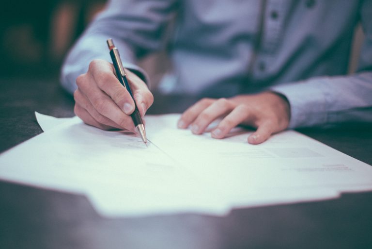 Hands holding a pen and writing on paper